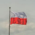 Flaga Polski powiewająca na wietrze na tle pochmurnego nieba