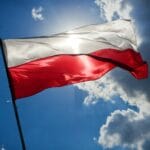 Powiewająca biało-czerwona flaga Polski na tle błękitnego nieba