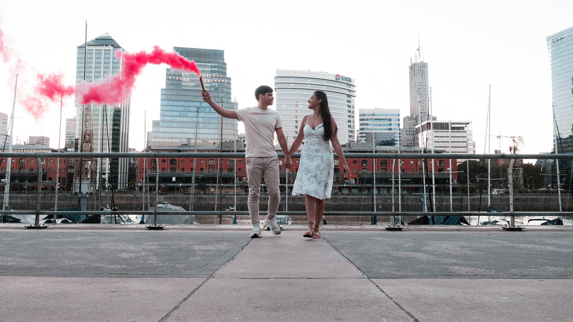 Para nad rzeką w Buenos Aires trzymająca czerwoną racę dymną