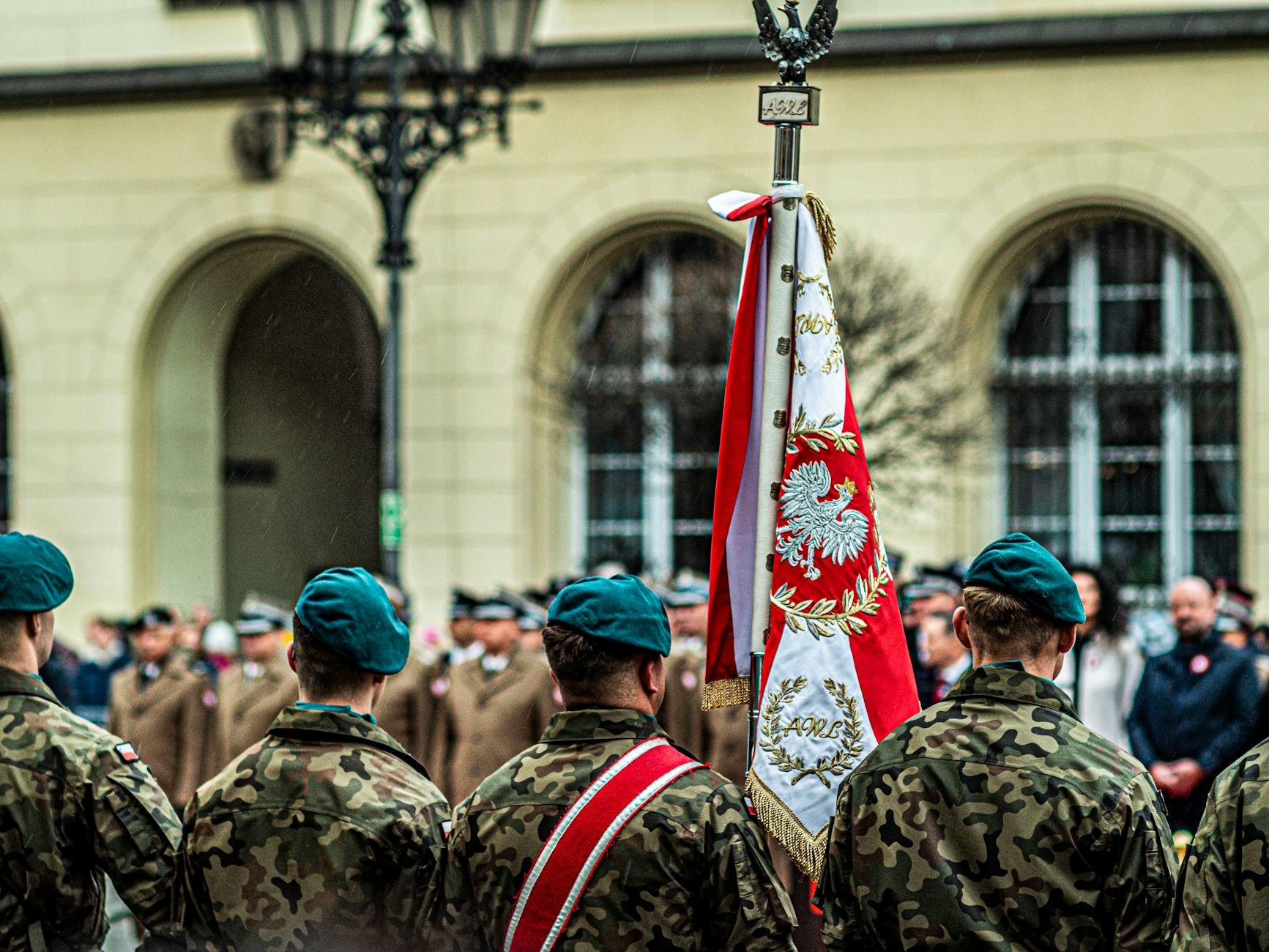 Polscy żołnierze w mundurach podczas uroczystej parady z flagą państwową