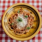 Talerz makaronu bolognese z parmezanem na kraciastym obrusie