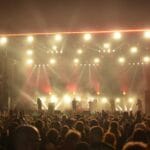 Koncert rockowy nocą, zespół na scenie i rozemocjonowana publiczność