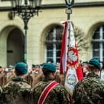 Polscy żołnierze w mundurach podczas uroczystej parady z biało-czerwoną flagą
