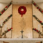 Ołtarz w kościele z czerwonym wieńcem bożonarodzeniowym i świecami